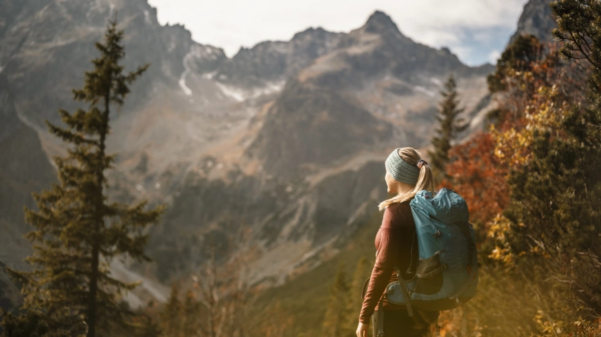 young traveler hiking girl with backpacks hiking mountains sunny landscape tourist traveler background view mockup high tatras slovakia