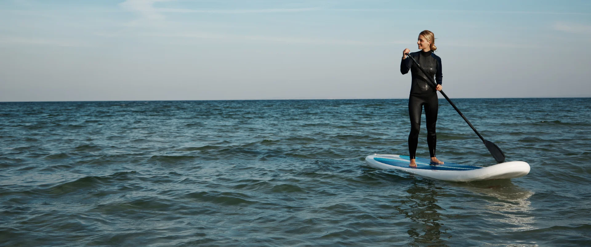 young blonde female paddleboard sea